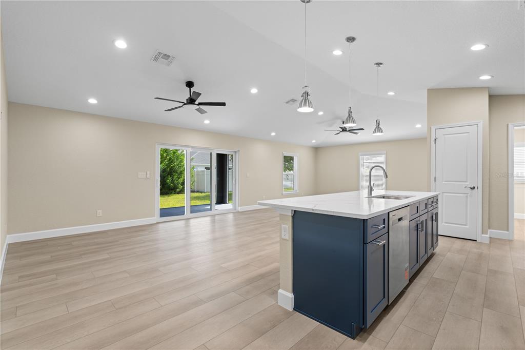 A kitchen island with blue cabinets and a white countertop sits in an open-concept room — 9417 HEARTWELLVILLE AVENUE, ENGLEWOOD, FL