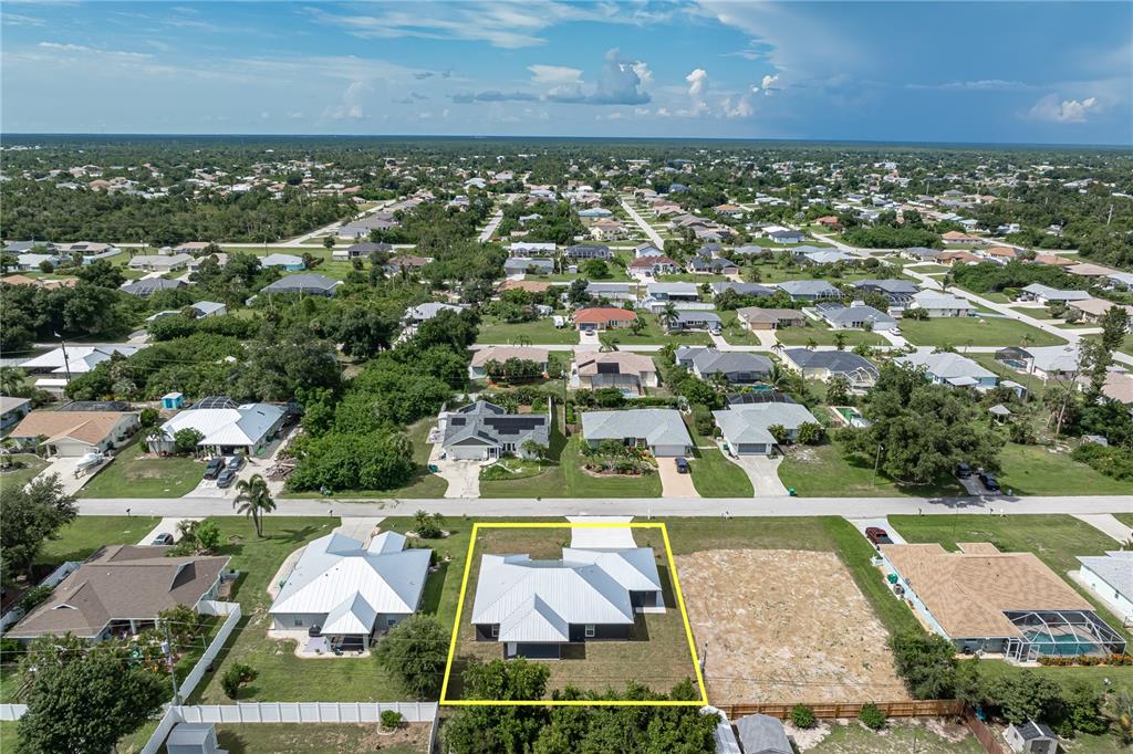 An aerial view shows a single-story house with a white roof on a residential lot — 9417 HEARTWELLVILLE AVENUE, ENGLEWOOD, FL
