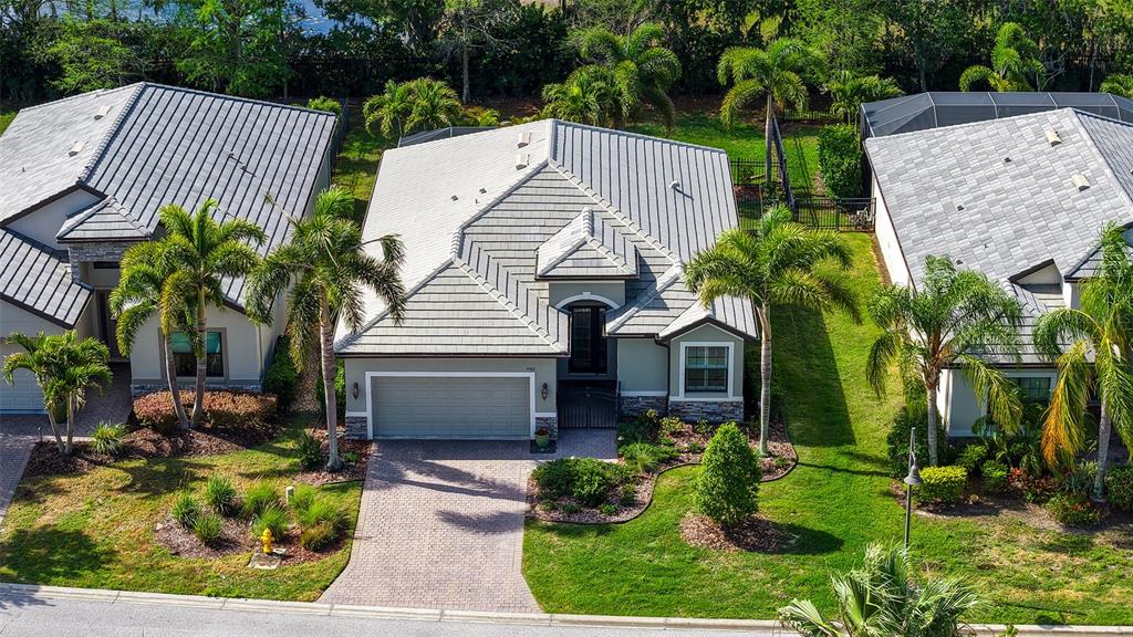 An aerial view shows a single-story house with a gray tiled roof and palm trees — 7702 RIO BELLA PLACE, BRADENTON, FL