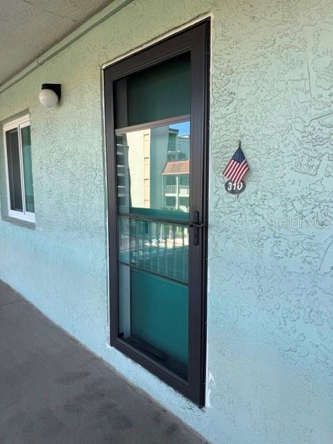 An exterior view of a teal-colored building with a dark-framed storm door and window — 801 83RD AVENUE N UNIT 310, ST PETERSBURG, FL