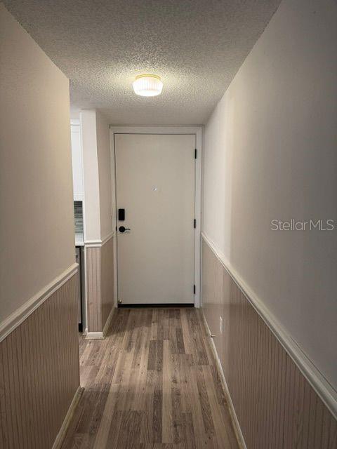 A hallway with wood-look flooring, wainscoting, and a white door leads to an entrance — 801 83RD AVENUE N UNIT 310, ST PETERSBURG, FL