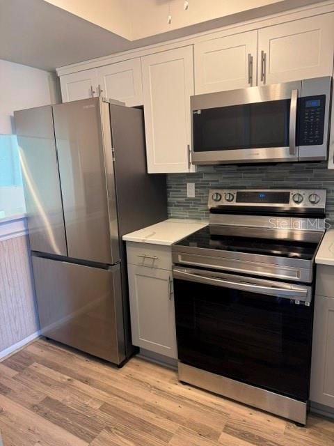 A kitchen features stainless steel appliances, white cabinetry, and wood-look flooring — 801 83RD AVENUE N UNIT 310, ST PETERSBURG, FL