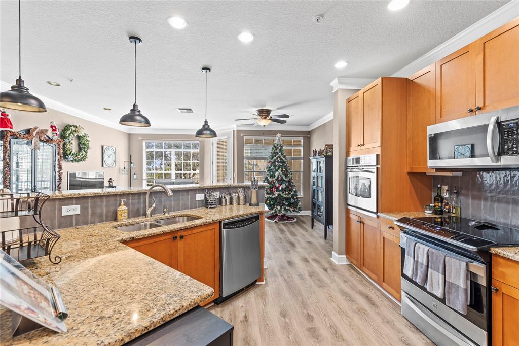 A kitchen with wood cabinets, granite countertops, stainless steel appliances, and a Christmas tree nearby — 6319 SUNSET BAY CIRCLE, APOLLO BEACH, FL