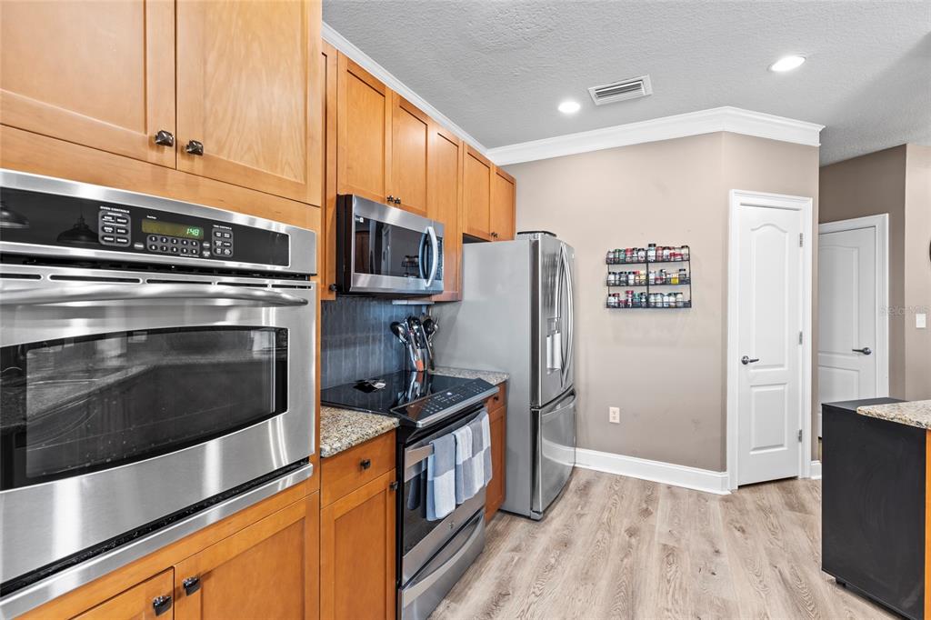 A kitchen features light wood cabinets, granite countertops, three pendant lights, and two bar stools — 6319 SUNSET BAY CIRCLE, APOLLO BEACH, FL