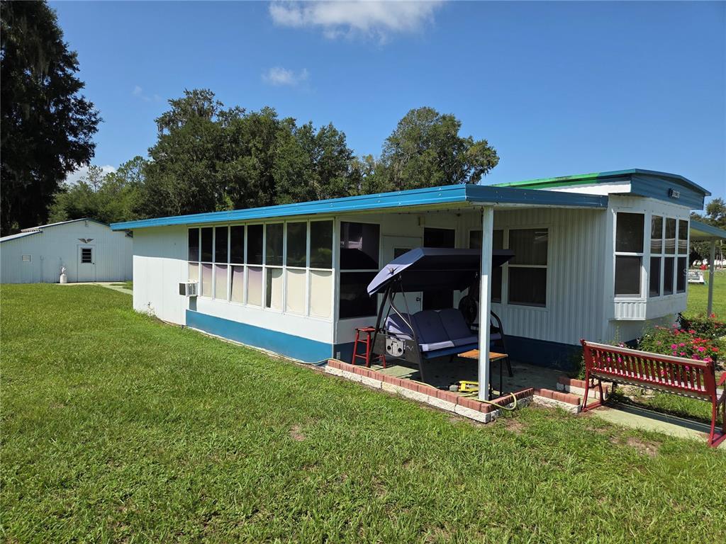 A mobile home with a screened-in porch, a blue roof, and a swing on the patio — 10228 SE 24TH STREET, WEBSTER, FL