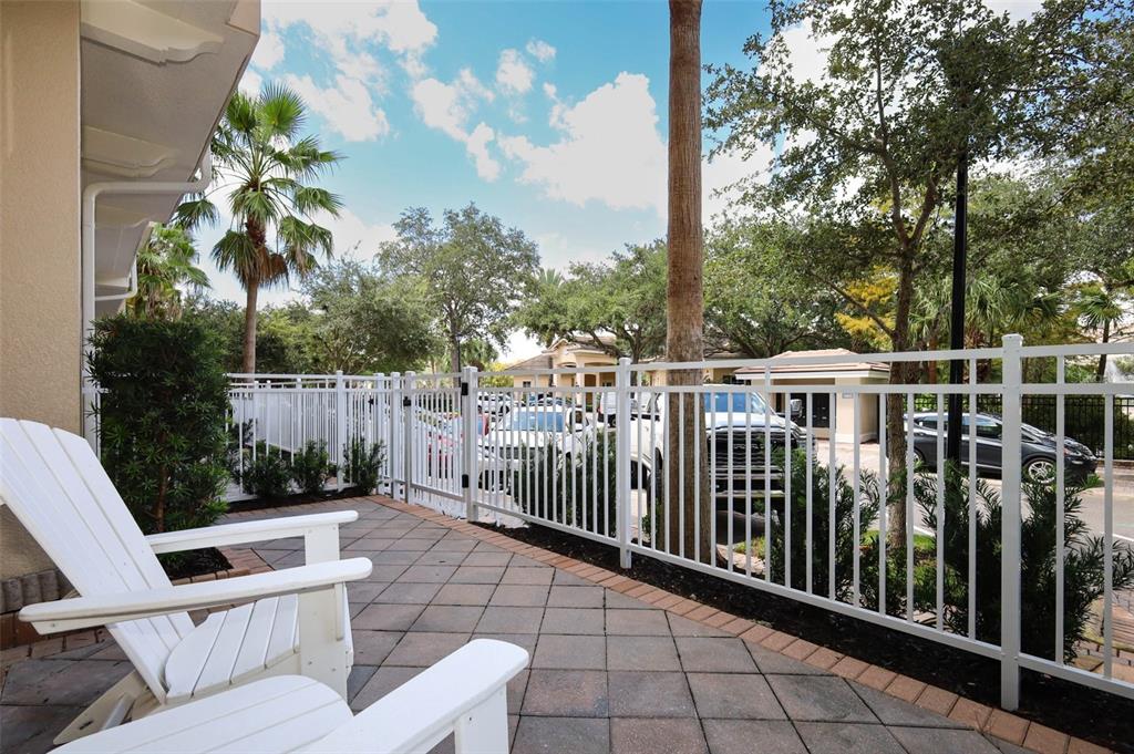 A white Adirondack chair sits on a paved patio enclosed by a white metal fence — 1465 LAKE GEORGE DRIVE, LAKE MARY, FL