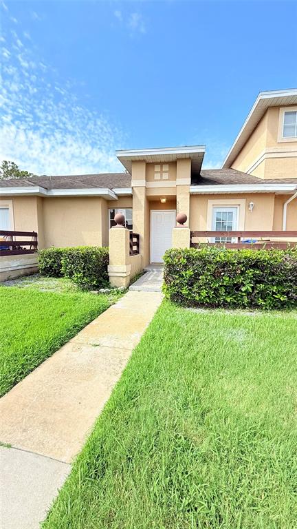 A tan house exterior features a concrete walkway leading to a white front door — 3104 LANDSEND COURT, KISSIMMEE, FL
