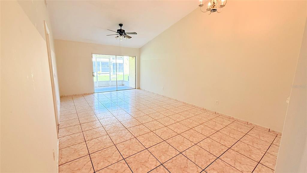 An empty room with light-colored tile flooring, a ceiling fan, and sliding glass patio doors — 3104 LANDSEND COURT, KISSIMMEE, FL
