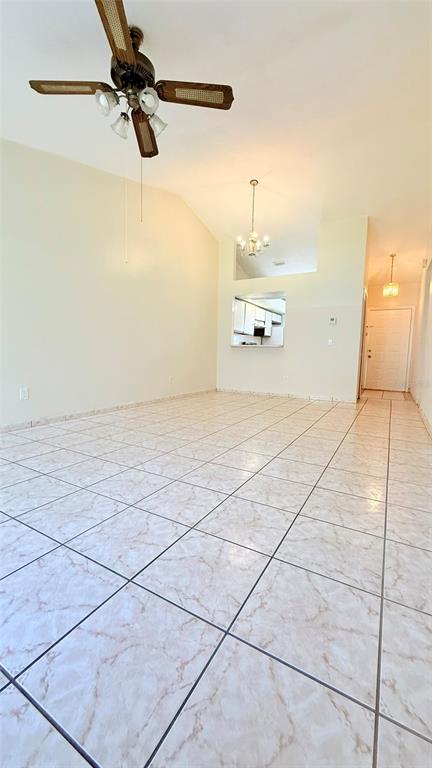 A spacious room with light-colored tile flooring, a ceiling fan, and a view into a kitchen — 3104 LANDSEND COURT, KISSIMMEE, FL