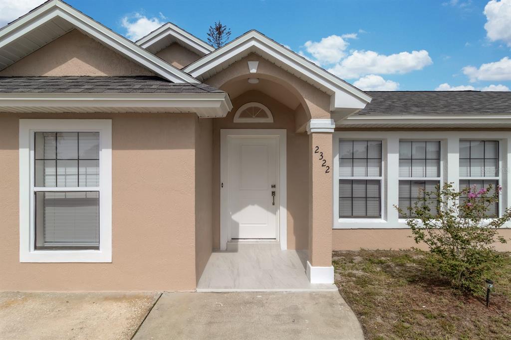 The exterior of a tan house features a white front door and a covered entryway — 2322 VINCENT ROAD, ORLANDO, FL