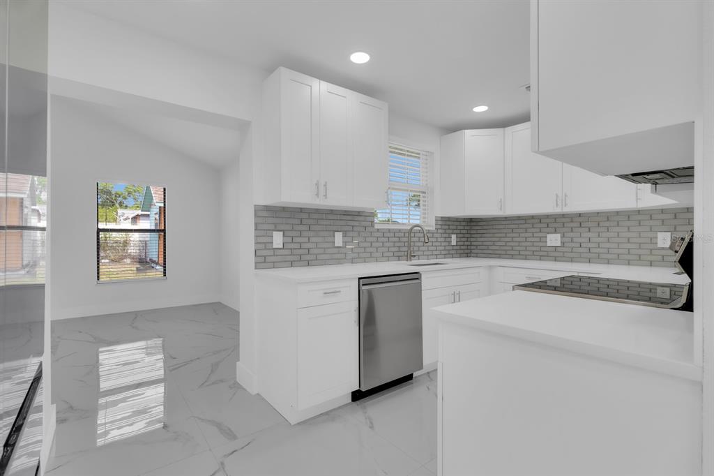 A modern kitchen features white cabinetry, gray subway tile backsplash, and light-colored marble-look floor tiles — 2322 VINCENT ROAD, ORLANDO, FL