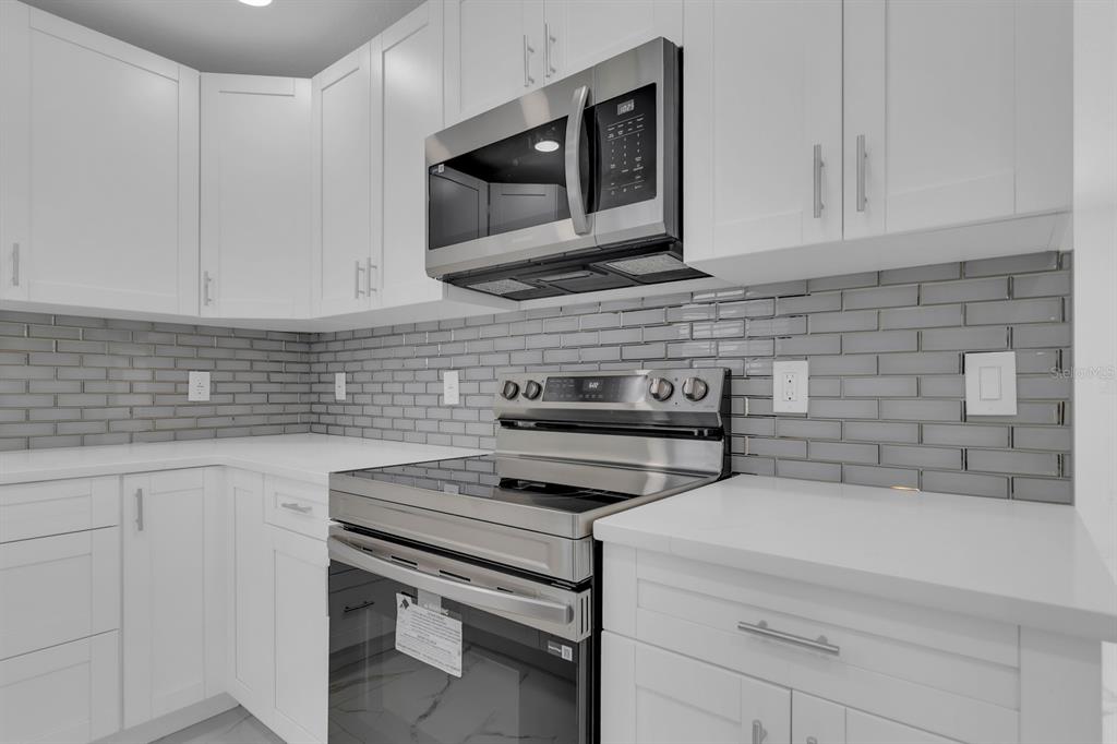 A kitchen with white cabinets, stainless steel appliances, and a gray subway tile backsplash — 2322 VINCENT ROAD, ORLANDO, FL