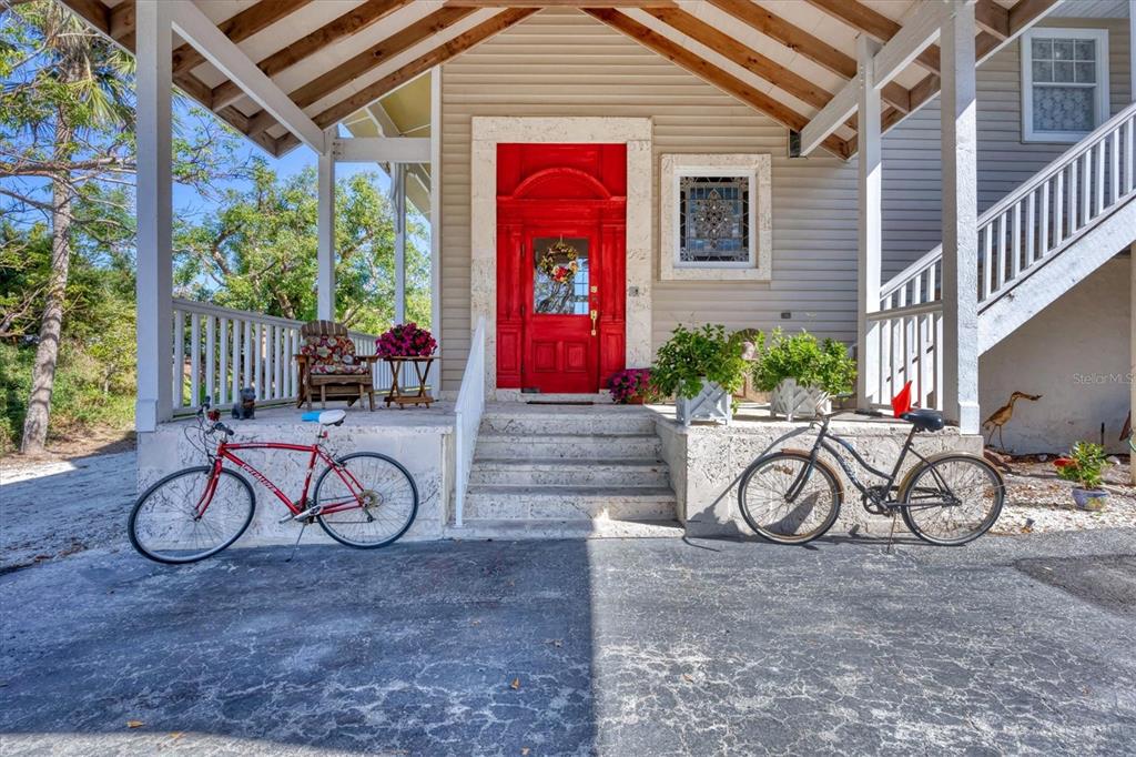 A red front door with a stained glass window sits under a covered porch — 1660 16TH STREET E, BOCA GRANDE, FL
