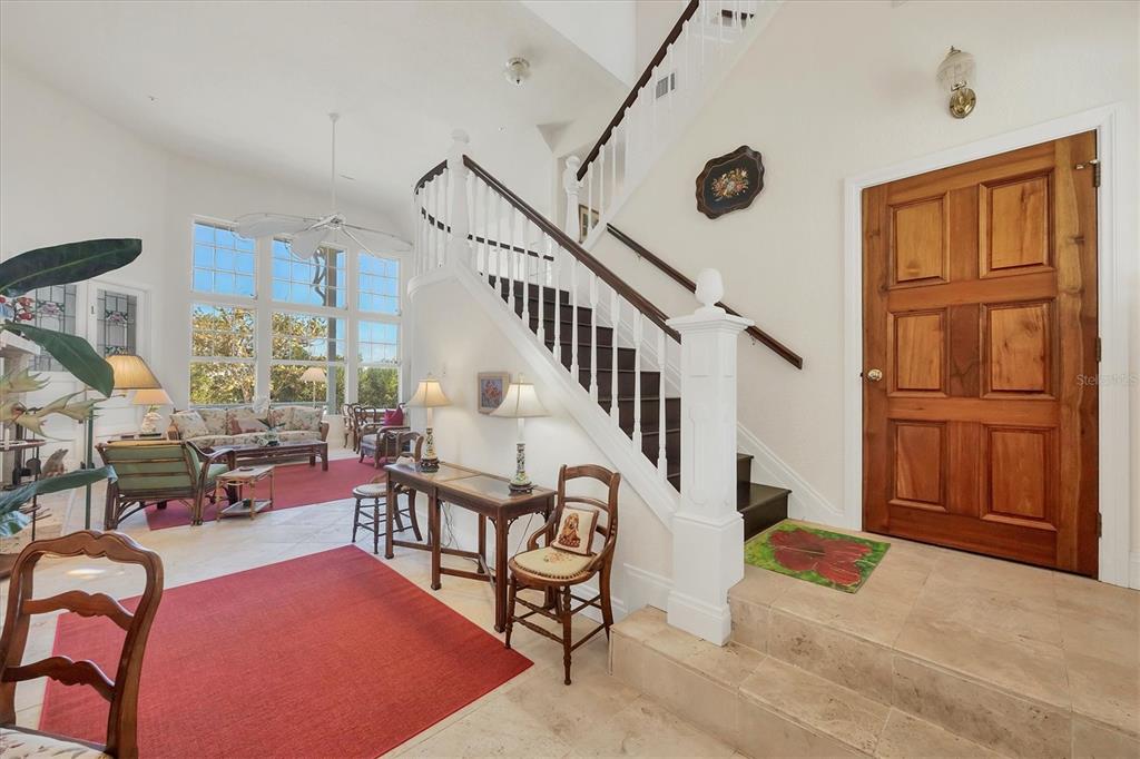A bright foyer features a wooden front door, a staircase, and tile flooring — 1660 16TH STREET E, BOCA GRANDE, FL