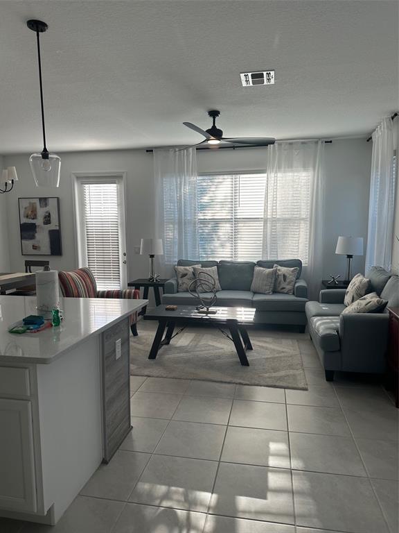 A living room with tile floors, a blue sofa, and a kitchen island in the foreground — 1546 DISCOVERY STREET, DAVENPORT, FL