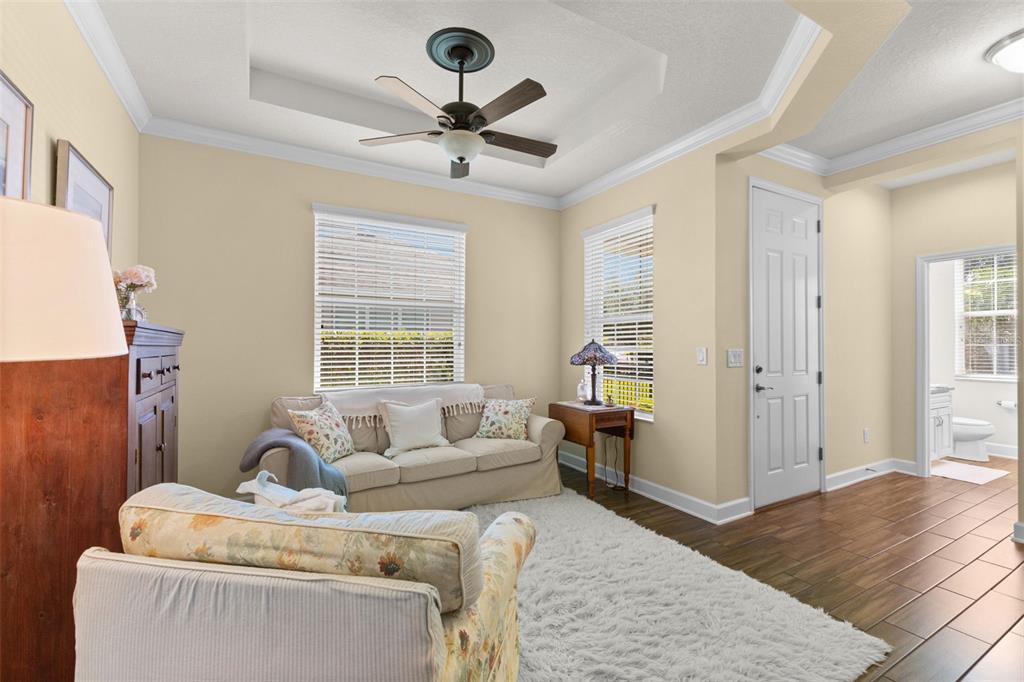 A living room features a beige sofa, floral armchair, white rug, and wood-look tile flooring — 6918 MAKERS WAY, APOLLO BEACH, FL