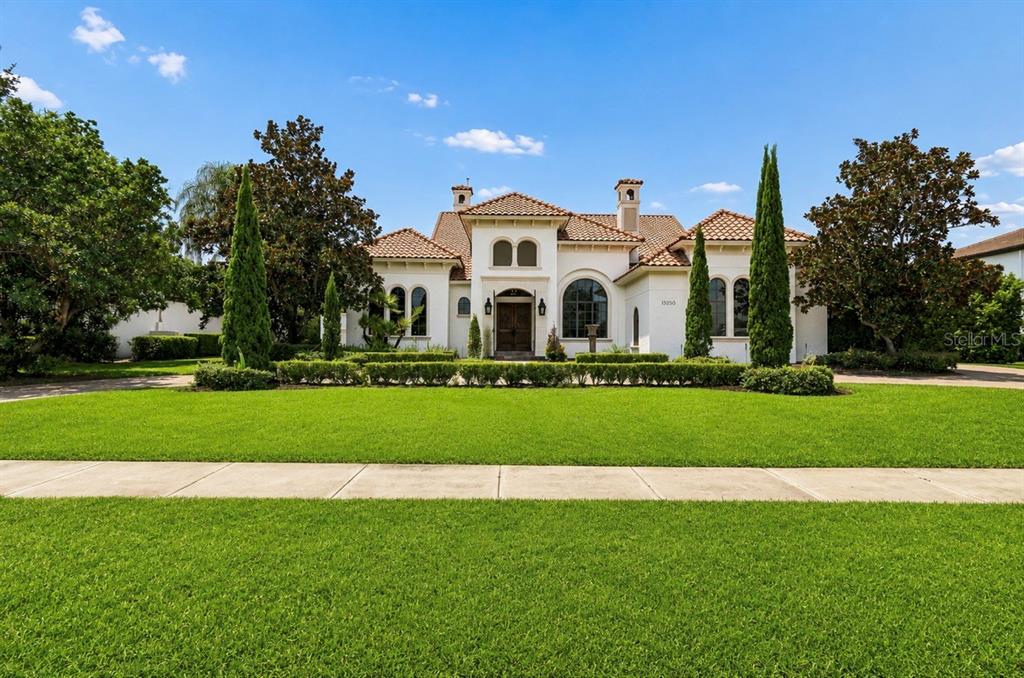 A Mediterranean-style house with a stucco exterior, tile roof, and manicured landscaping — 13250 BELLARIA CIRCLE, WINDERMERE, FL