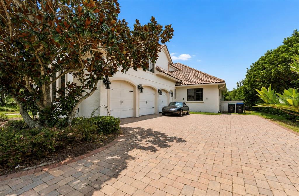 A three-car garage with a paved driveway and a parked car in front — 13250 BELLARIA CIRCLE, WINDERMERE, FL