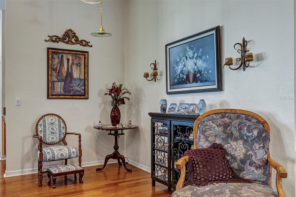 A room with hardwood floors, two patterned armchairs, a small round table, and wall art — 11003 SW 69TH CIRCLE, OCALA, FL