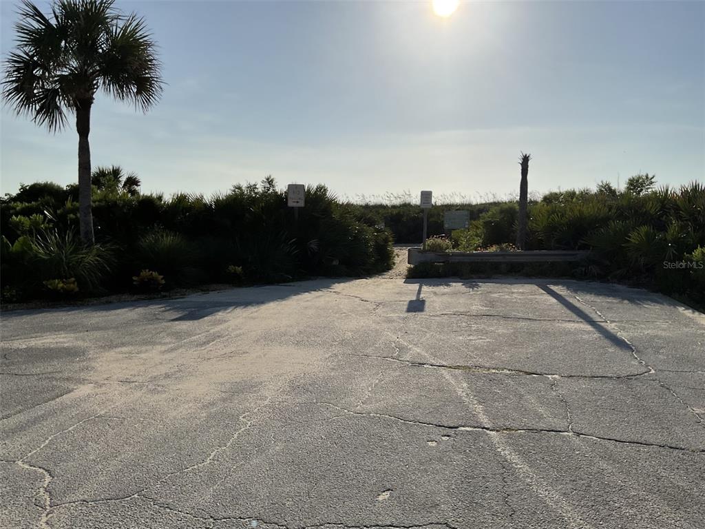 A paved parking area leads to a sandy path through vegetation toward the beach — 5 DOGWOOD TERRACE, PALM COAST, FL