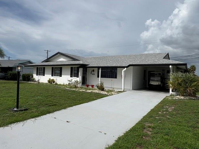 A single-story house with a white exterior, a gray roof, and a concrete driveway — 1021 AUGUSTA DRIVE, SUN CITY CENTER, FL