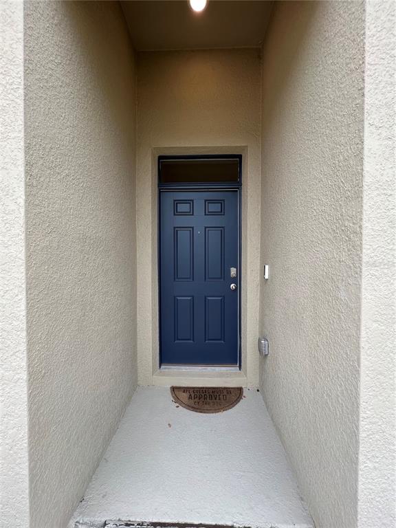 A blue front door with a transom window is set within a recessed stucco entryway — 4032 GREY HERON LOOP, BARTOW, FL