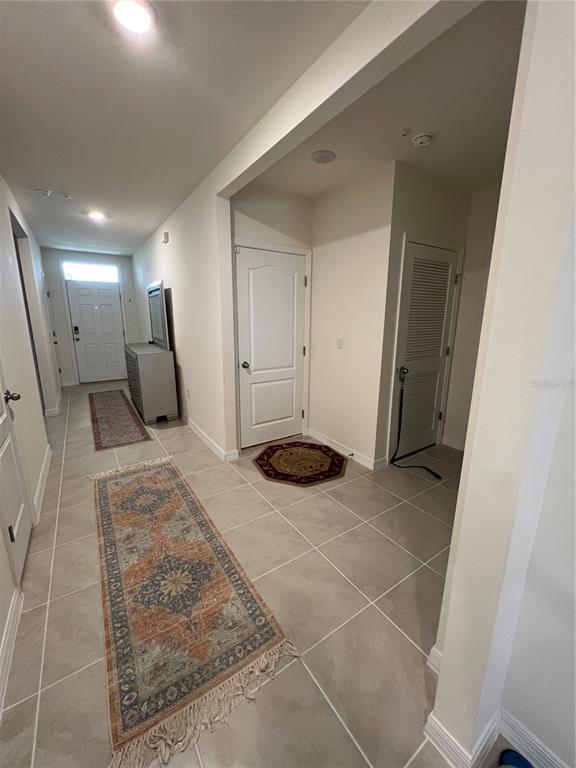 A tiled hallway features two area rugs, a dresser, and several white interior doors — 4032 GREY HERON LOOP, BARTOW, FL