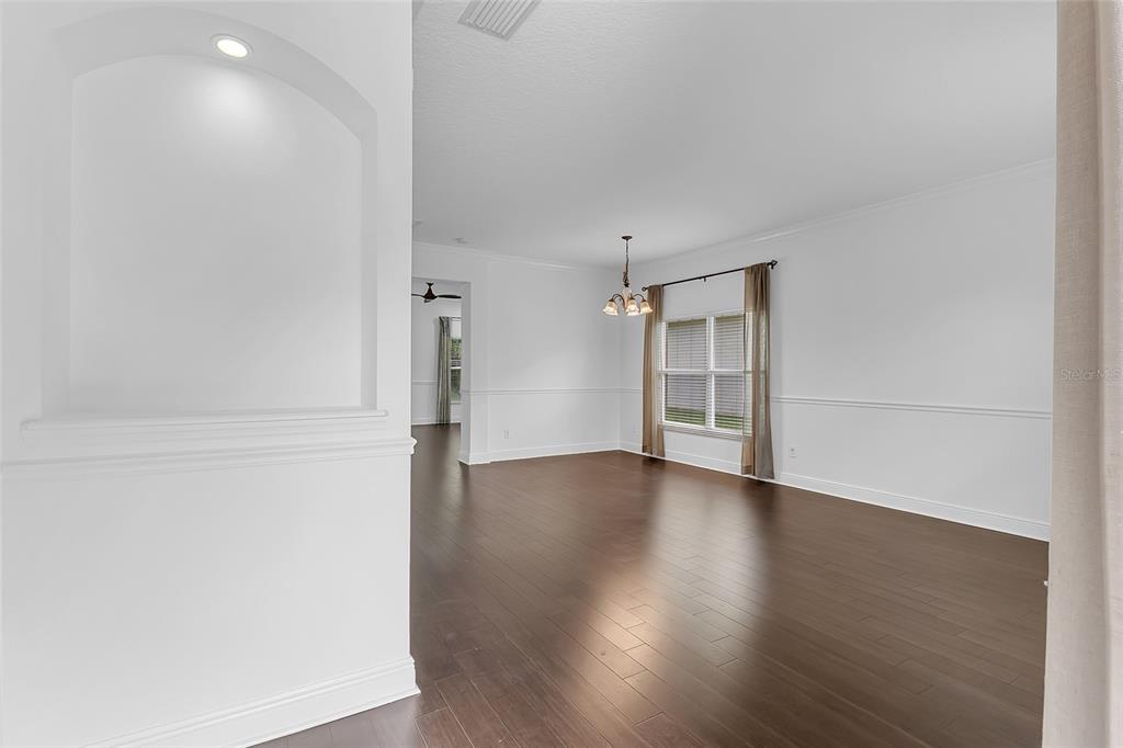 An empty dining room with dark wood floors, white walls, and a chandelier — 1127 CRANE CREST WAY, ORLANDO, FL