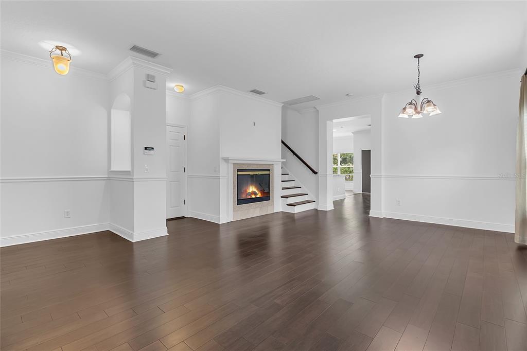 A living room with dark wood floors, a fireplace, and a staircase — 1127 CRANE CREST WAY, ORLANDO, FL