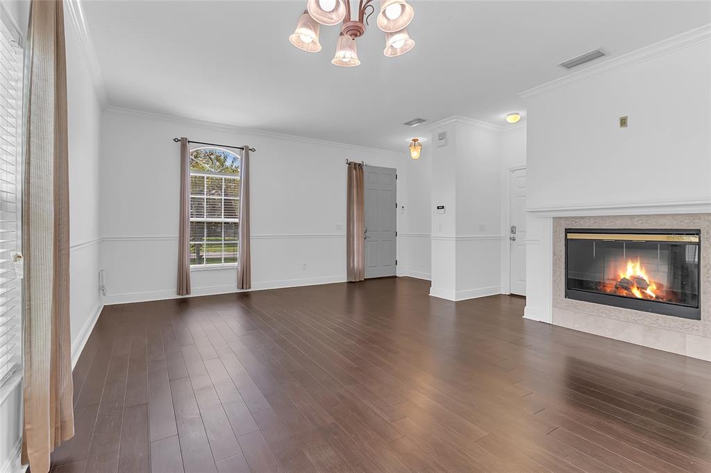 A living room features dark hardwood floors, white walls, a fireplace, and a chandelier — 1127 CRANE CREST WAY, ORLANDO, FL