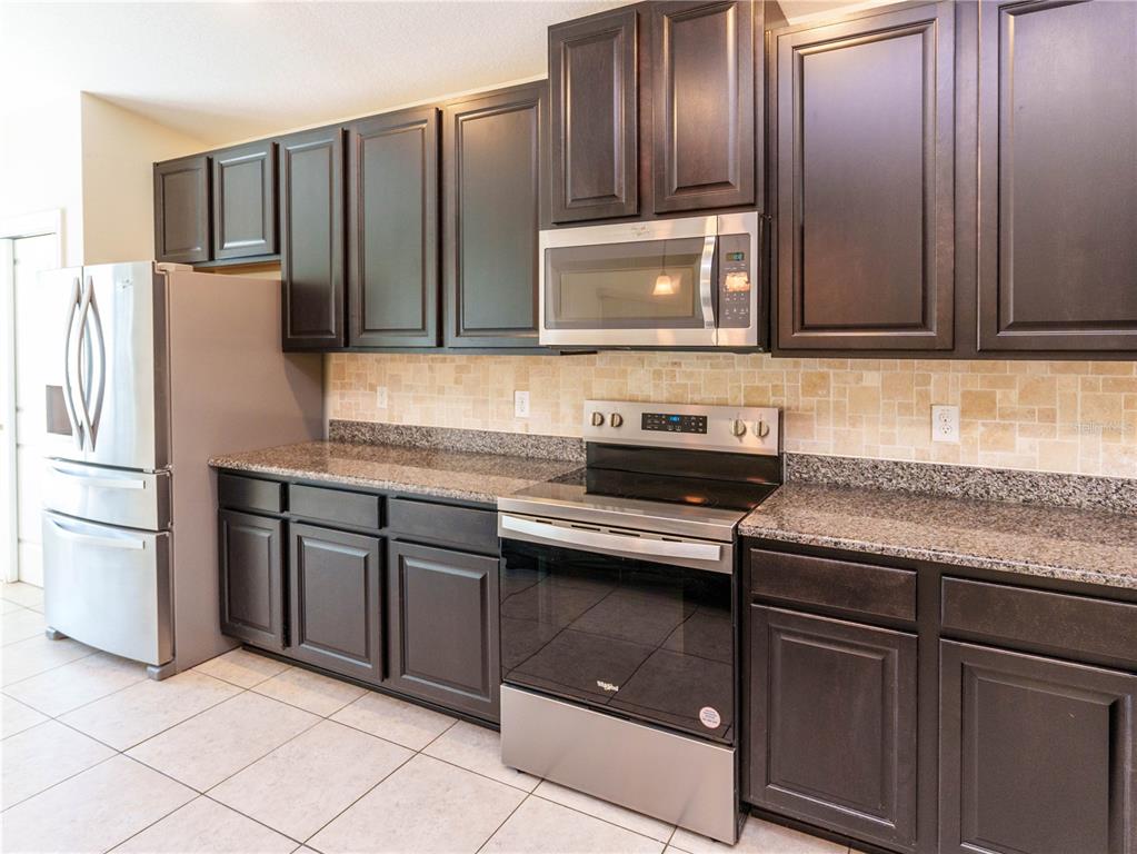 A living room features a large brown sectional sofa, an entertainment center, and tile flooring — 14148 FINSBURY DRIVE, SPRING HILL, FL