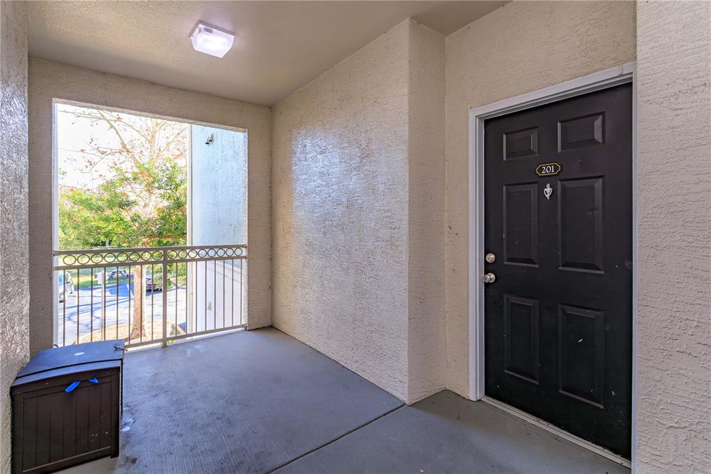 An apartment entryway features a dark door numbered 201, a balcony, and a storage bin — 12849 MADISON POINT CIRCLE UNIT 201, ORLANDO, FL