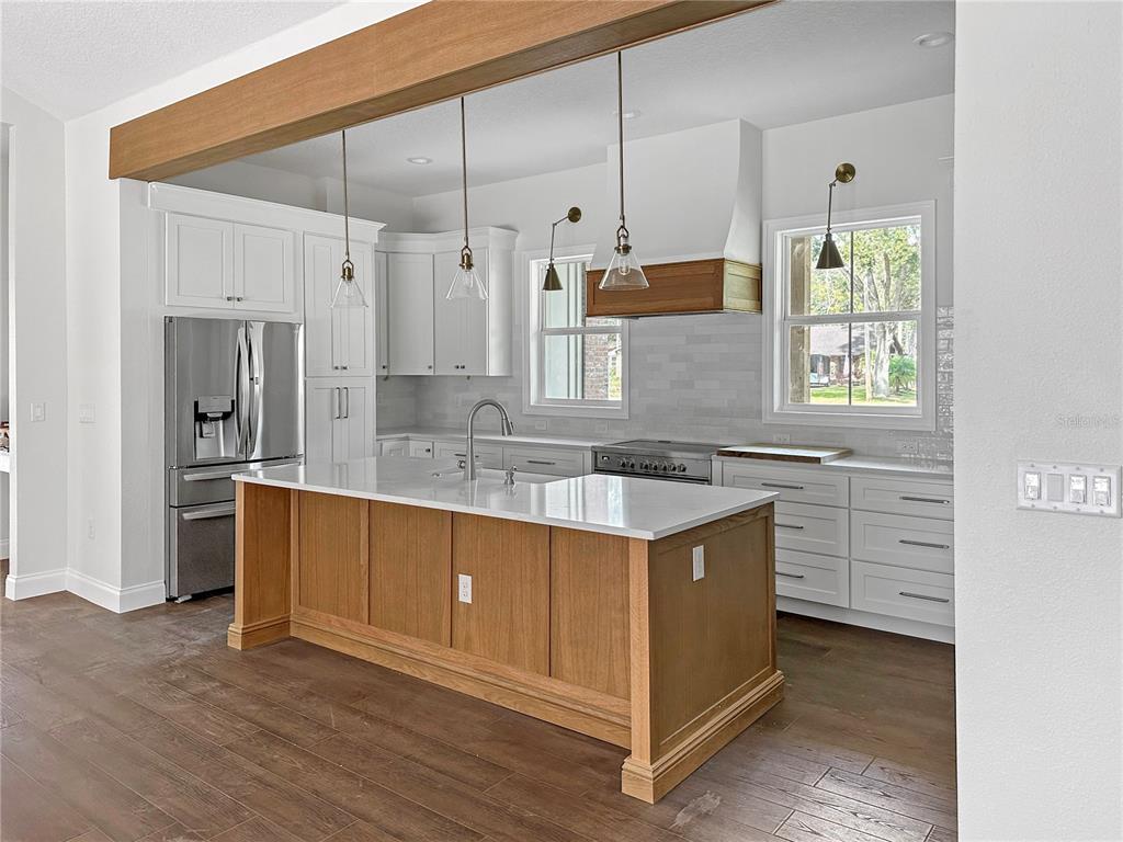 A kitchen features a wood-toned island, white cabinetry, stainless steel appliances, and a wooden beam — 935 N THOMPSON ROAD, APOPKA, FL