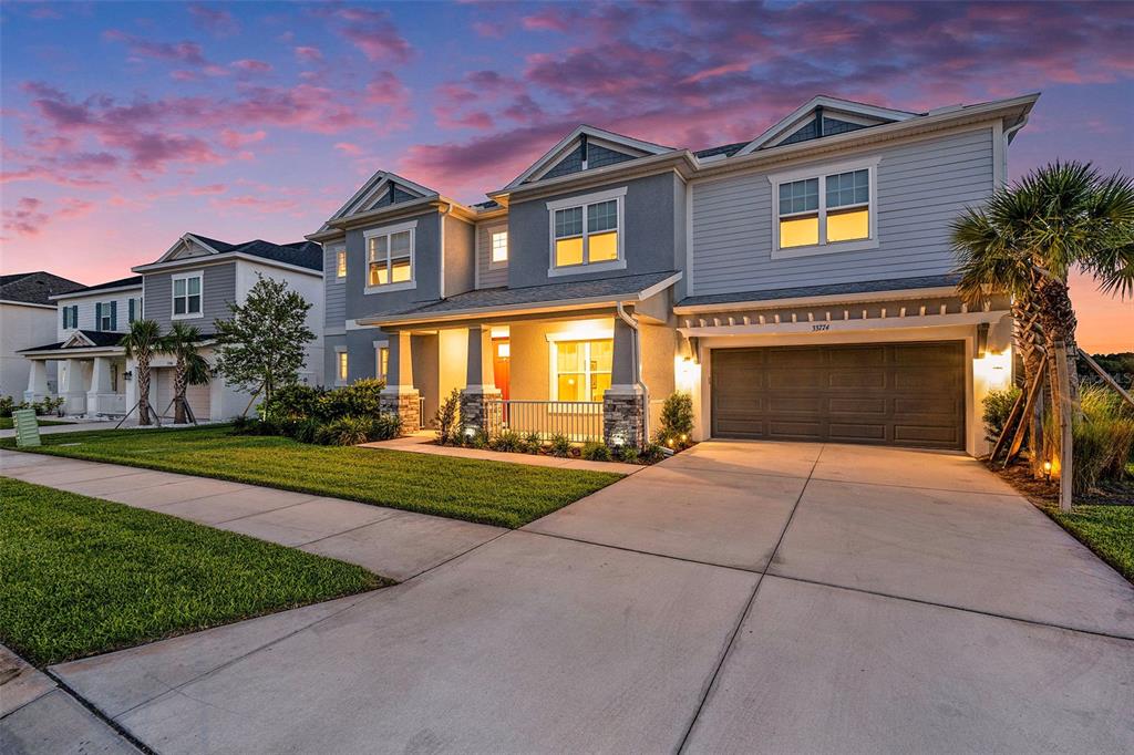 A two-story suburban house with a gray exterior, a two-car garage, and a front porch — 33774 CASTAWAY LOOP, WESLEY CHAPEL, FL