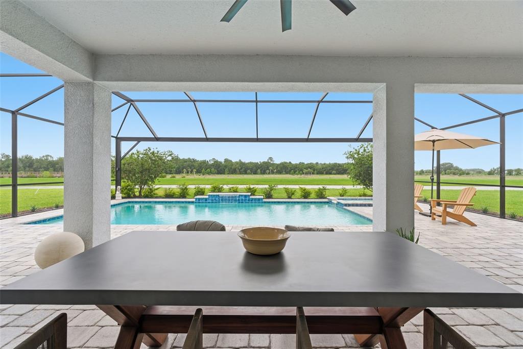 A covered patio features a dining table, a swimming pool, and a screened-in outdoor area — 33774 CASTAWAY LOOP, WESLEY CHAPEL, FL