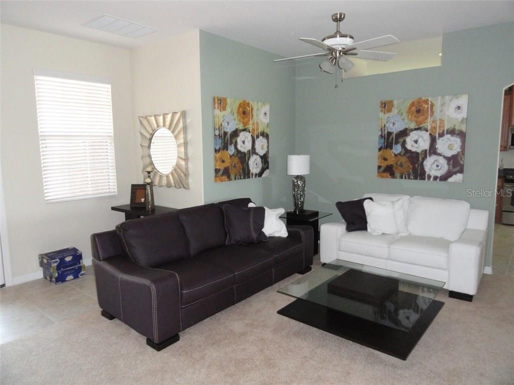 A living room features a dark sofa, a white sofa, and floral wall art — 115 RIVER ENCLAVE CT. COURT, BRADENTON, FL
