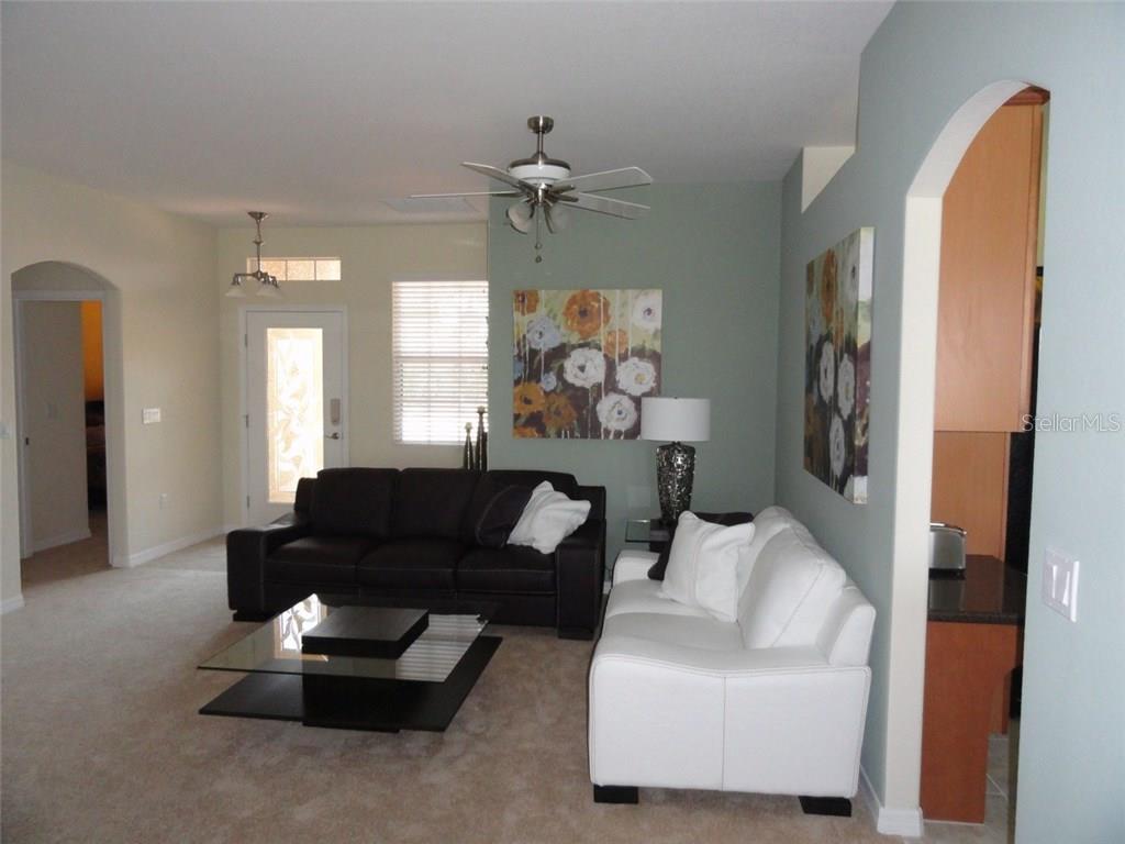 A living room features a dark sofa, a white sofa, and a glass coffee table — 115 RIVER ENCLAVE CT. COURT, BRADENTON, FL