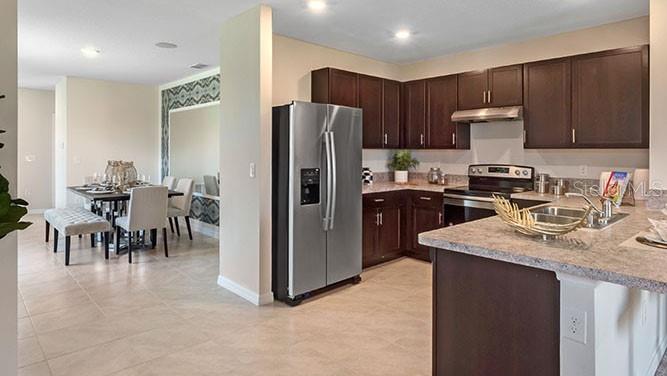 A kitchen with dark wood cabinets, stainless steel appliances, and an island overlooks a dining area — 8310 PONCE DE LEON STREET, LAKELAND, FL
