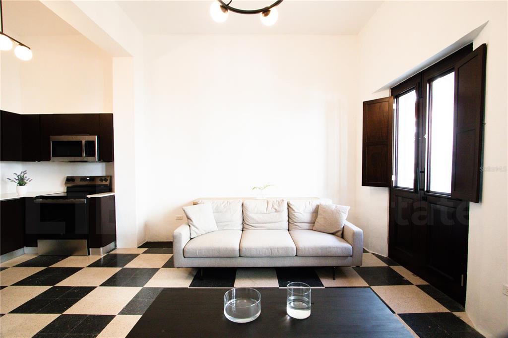 A living room features a grey sofa, a black coffee table, and black-and-white checkered floors — 254-256 SAN FRANCISCO STREET UNIT 201, SAN JUAN, PR