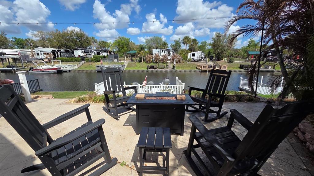 A patio with four black rocking chairs and a fire pit overlooks a canal — 431 WATERWAY DRIVE, RIVER RANCH, FL