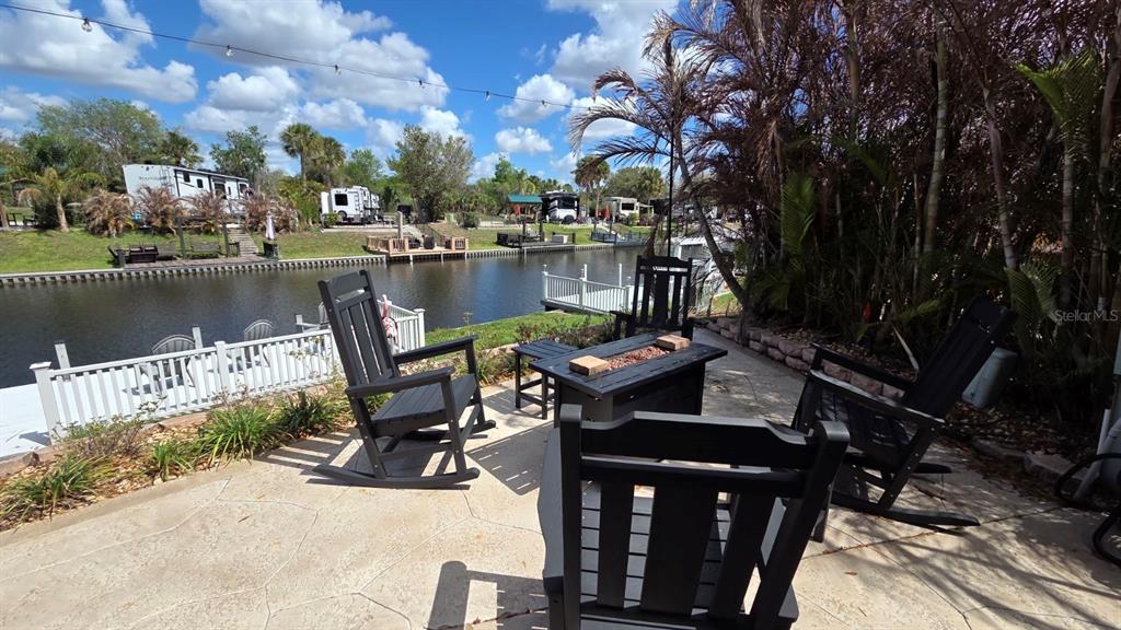 A patio with black rocking chairs and a fire pit overlooks a canal and boats — 431 WATERWAY DRIVE, RIVER RANCH, FL