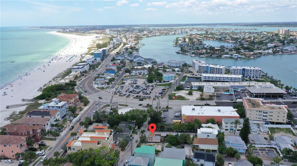 An aerial view shows a coastal neighborhood with colorful houses, palm trees, and a waterway — 101 95TH AVENUE, TREASURE ISLAND, FL