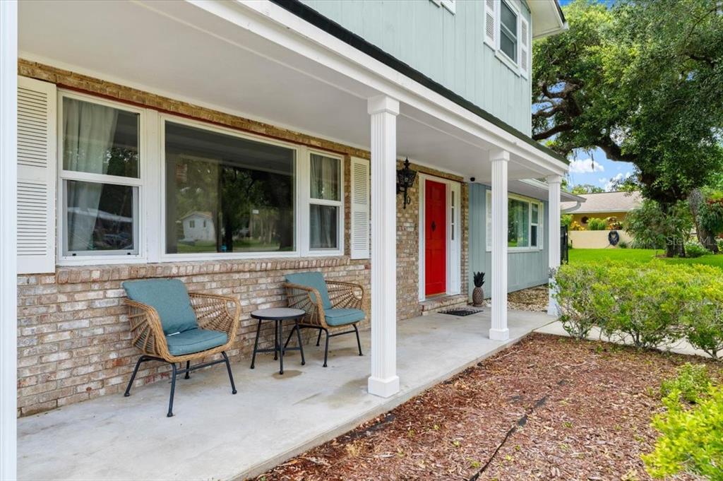 A covered front porch with two wicker chairs, a small table, and a red door — 20 PUTNAM AVENUE, ORMOND BEACH, FL