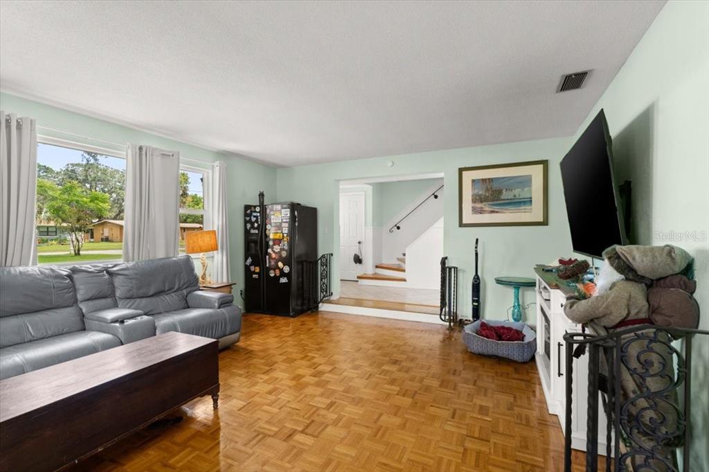A living room features parquet wood flooring, a grey leather sofa, and a wall-mounted television — 20 PUTNAM AVENUE, ORMOND BEACH, FL