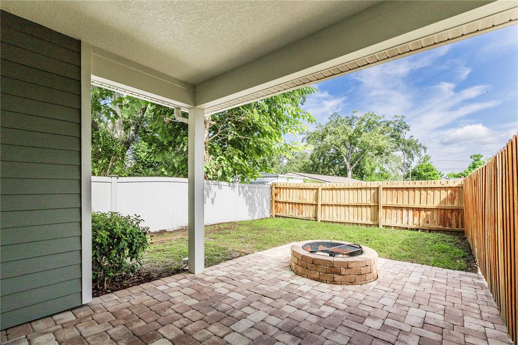 A covered patio features a brick paver floor, a stone fire pit, and a fenced yard — 1407 E MURIEL STREET, ORLANDO, FL
