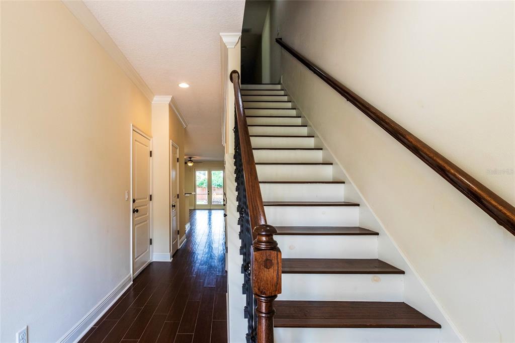 A staircase with dark wood treads and a decorative metal railing leads to an upper floor — 1407 E MURIEL STREET, ORLANDO, FL