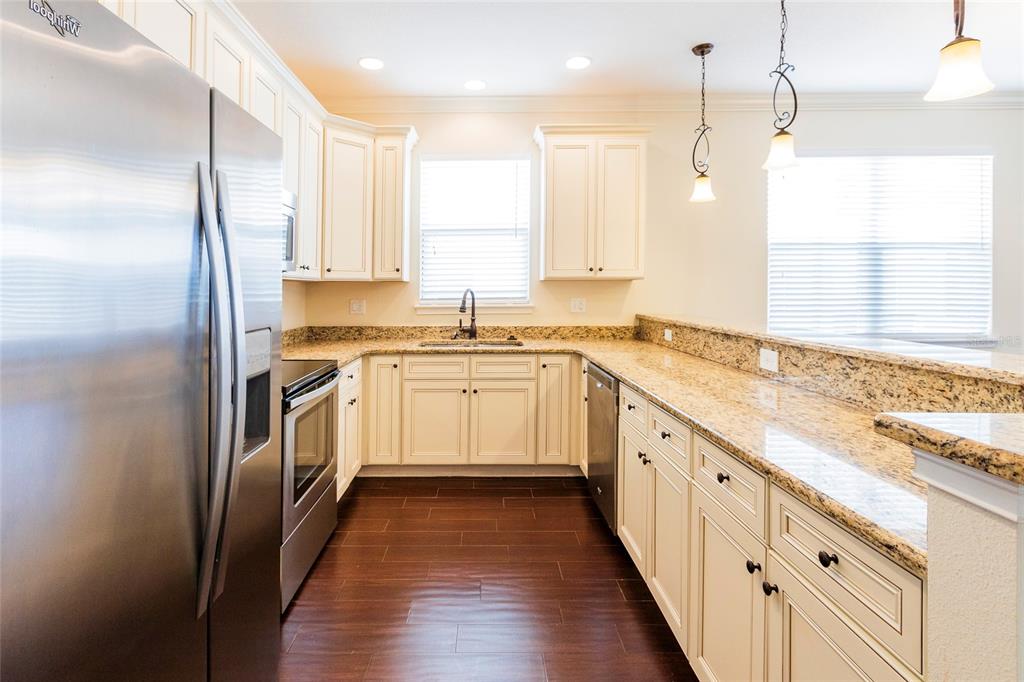 A kitchen with white cabinets, granite countertops, stainless steel appliances, and dark wood flooring — 1407 E MURIEL STREET, ORLANDO, FL
