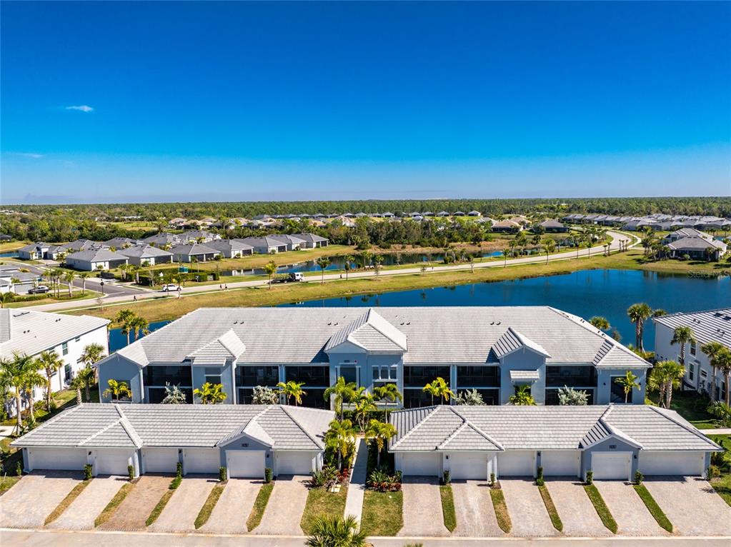 A concrete walkway leads between two multi-story apartment buildings with screened-in porches and landscaping — 14267 HERITAGE LANDING BOULEVARD UNIT 1212, PUNTA GORDA, FL