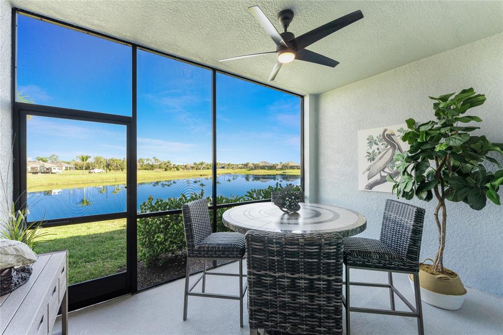 A screened-in patio features a dining set, a ceiling fan, and a view of a lake — 14267 HERITAGE LANDING BOULEVARD UNIT 1212, PUNTA GORDA, FL