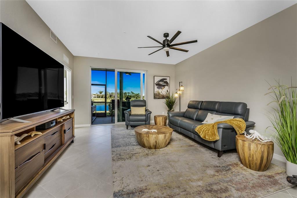 A living room features a grey sofa, wooden coffee tables, and a view of a lake — 14267 HERITAGE LANDING BOULEVARD UNIT 1212, PUNTA GORDA, FL